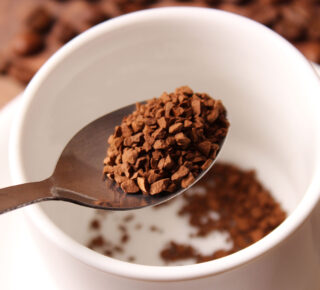 spoon with instant coffee granules over white mug